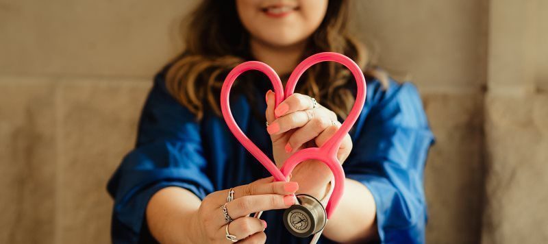 Medical Assistant holding a stethoscope in the shape of a heart.