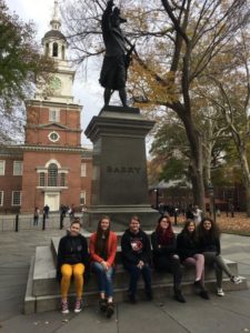Students sitting outside in front of a statue.